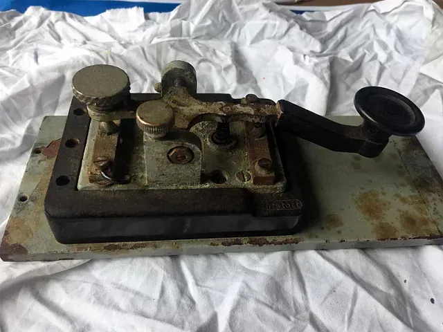 Una llave vieja reposa sobre un mantel blanco sobre una mesa.