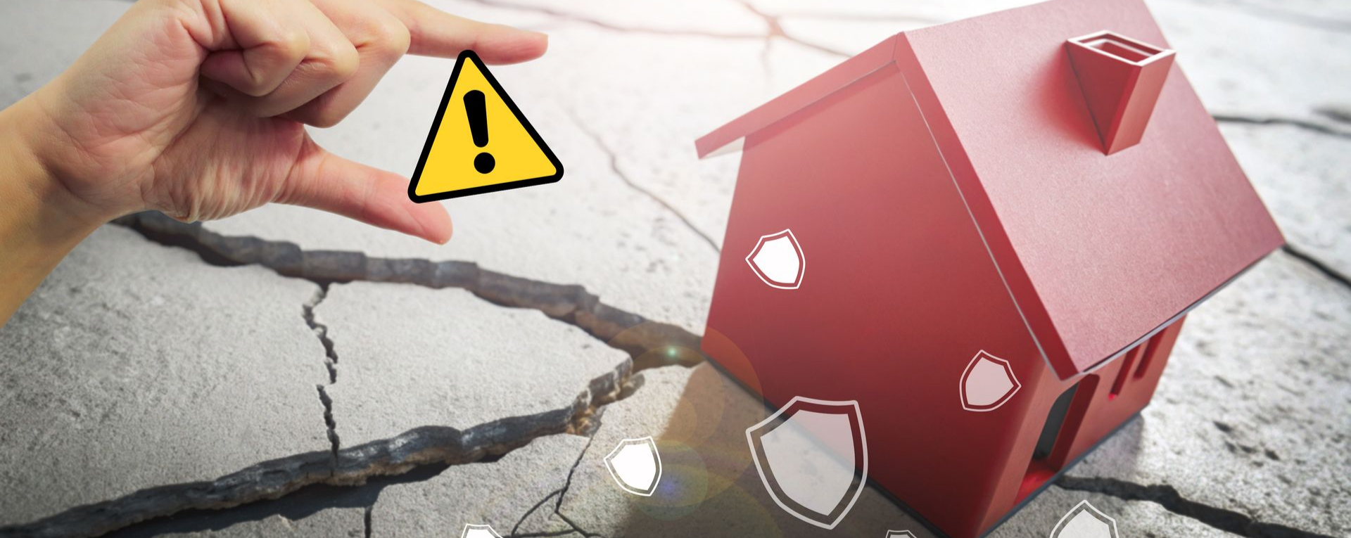 Main tenant un panneau d'avertissement au-dessus d'un sol fissuré et d'une maison miniature