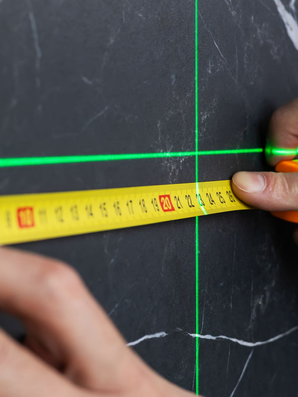 Mains utilisant un ruban à mesurer pour mesurer le long d'une grille laser
