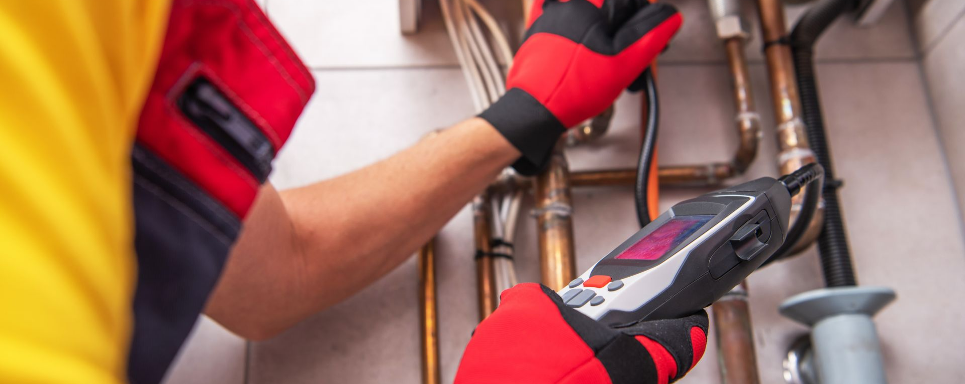 Une personne inspecte des tuyaux avec un appareil numérique