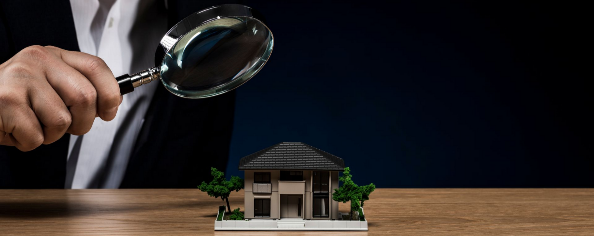Une personne inspectant une maison modèle avec une loupe