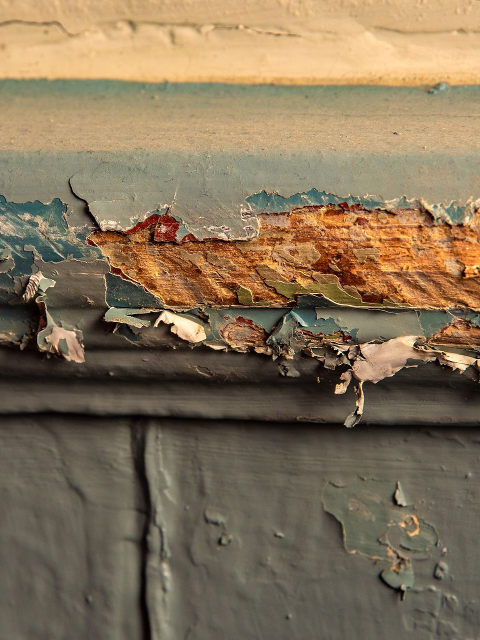 Peinture bleue écaillée révélant du bois en dessous sur un mur