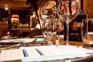 Une table dressée pour un dîner avec des verres de vin et un menu.