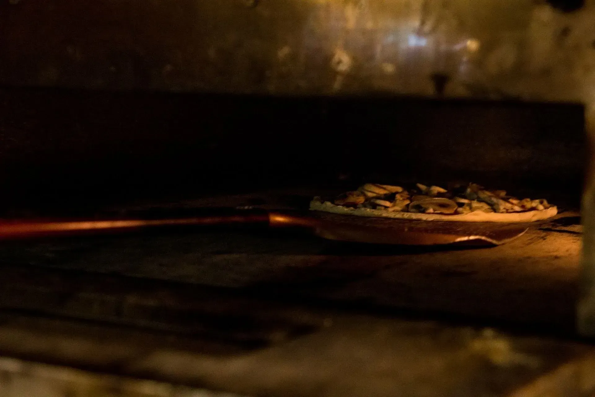 Une pizza est en train de cuire dans un four à bois.