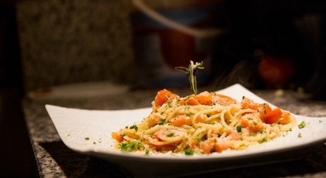 Une assiette de pâtes aux crevettes et aux tomates sur une table.