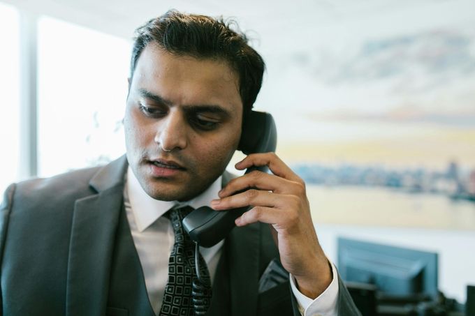 Un hombre con traje habla por teléfono en una oficina, con expresión concentrada.
