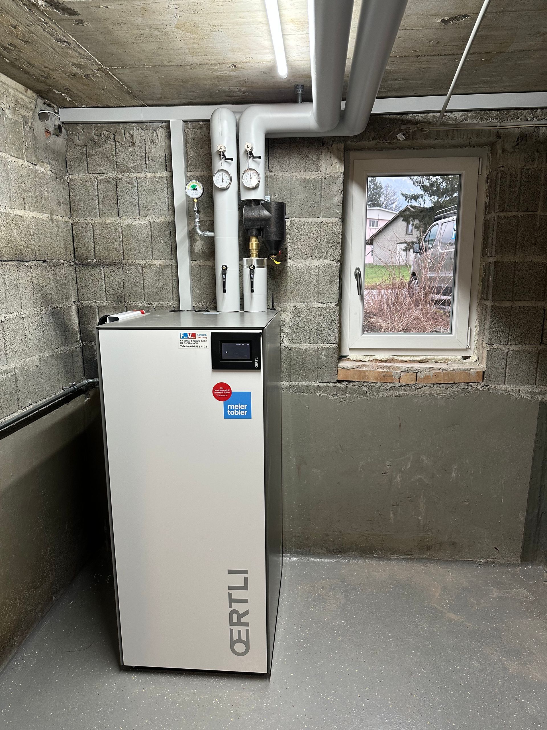 Ein Klempner benutzt einen Schraubenschlüssel an einem Abflussrohr eines Waschbeckens in einem Badezimmer mit grauen Fliesen.