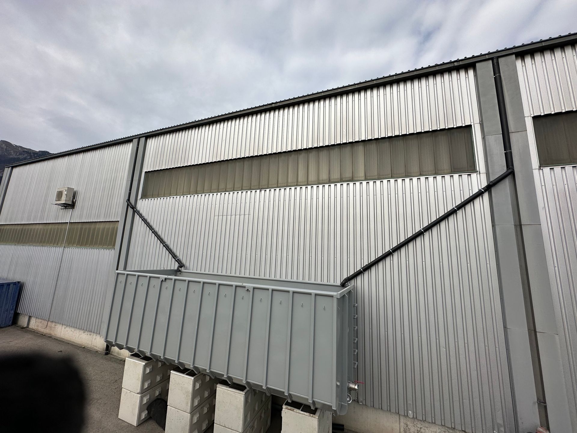 Ein Klempner arbeitet unter einem weissen Waschbecken im Badezimmer und benutzt einen Schraubenschlüssel.