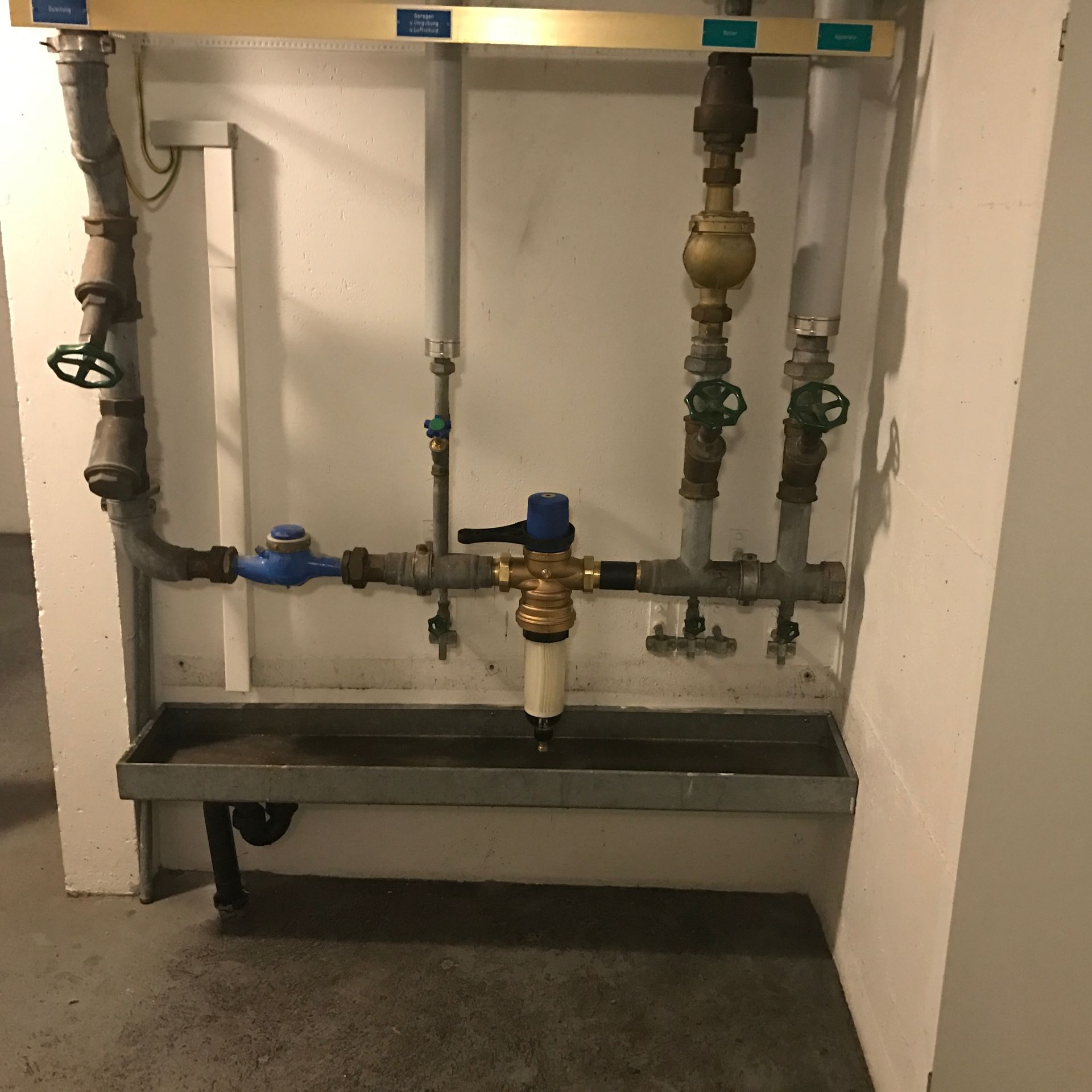 Ein Klempner mit Handschuhen benutzt einen Schraubenschlüssel an einem Abflussrohr eines Waschbeckens im Badezimmer.