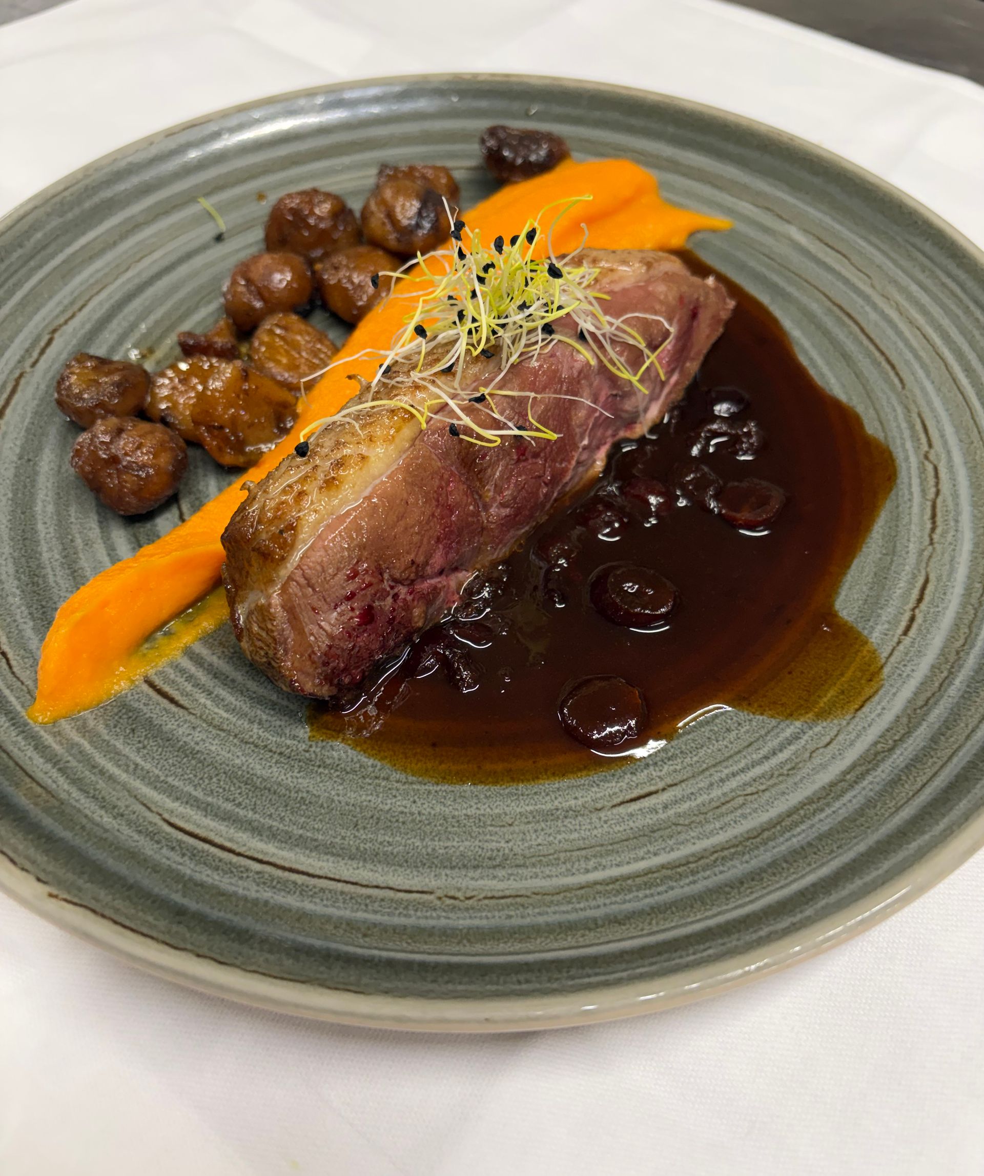 Steak poêlé servi avec sauce aux champignons, purée d'orange et champignons rôtis sur une assiette grise