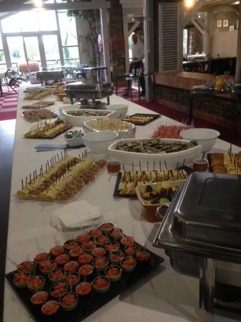 Un buffet garni d'amuse-gueules et de desserts variés est dressé dans une salle à manger lumineuse.