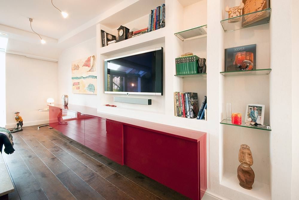 Ein Wohnzimmer mit einem roten Entertainment-Center und einem Flachbildfernseher.
