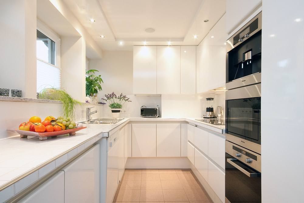 Eine Küche mit weißen Schränken, Geräten aus Edelstahl und einer Obstschale auf der Theke.