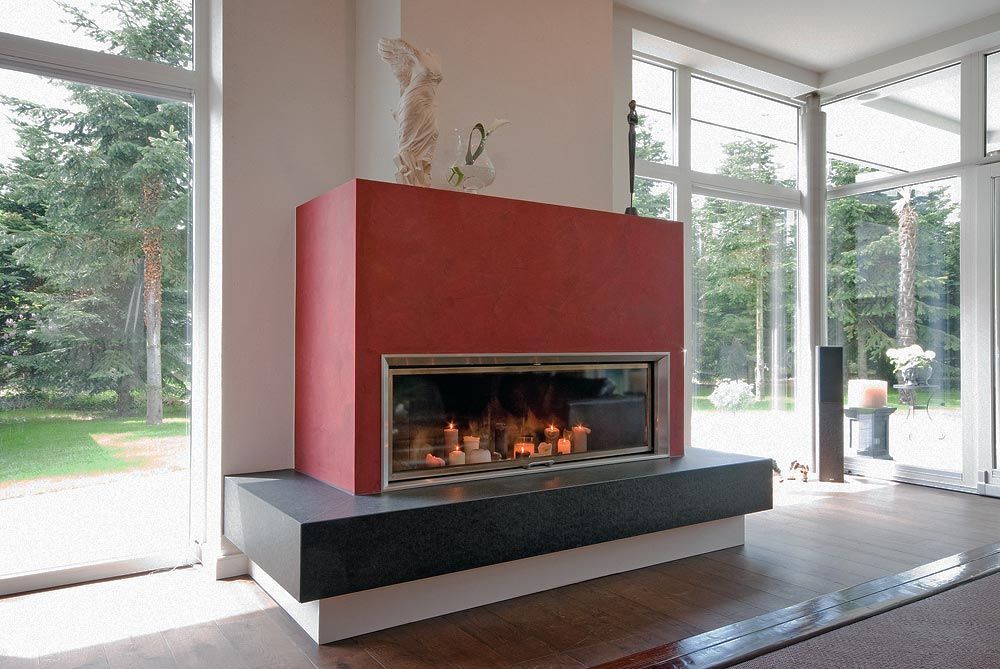 Ein roter Kamin in einem Wohnzimmer mit vielen Fenstern