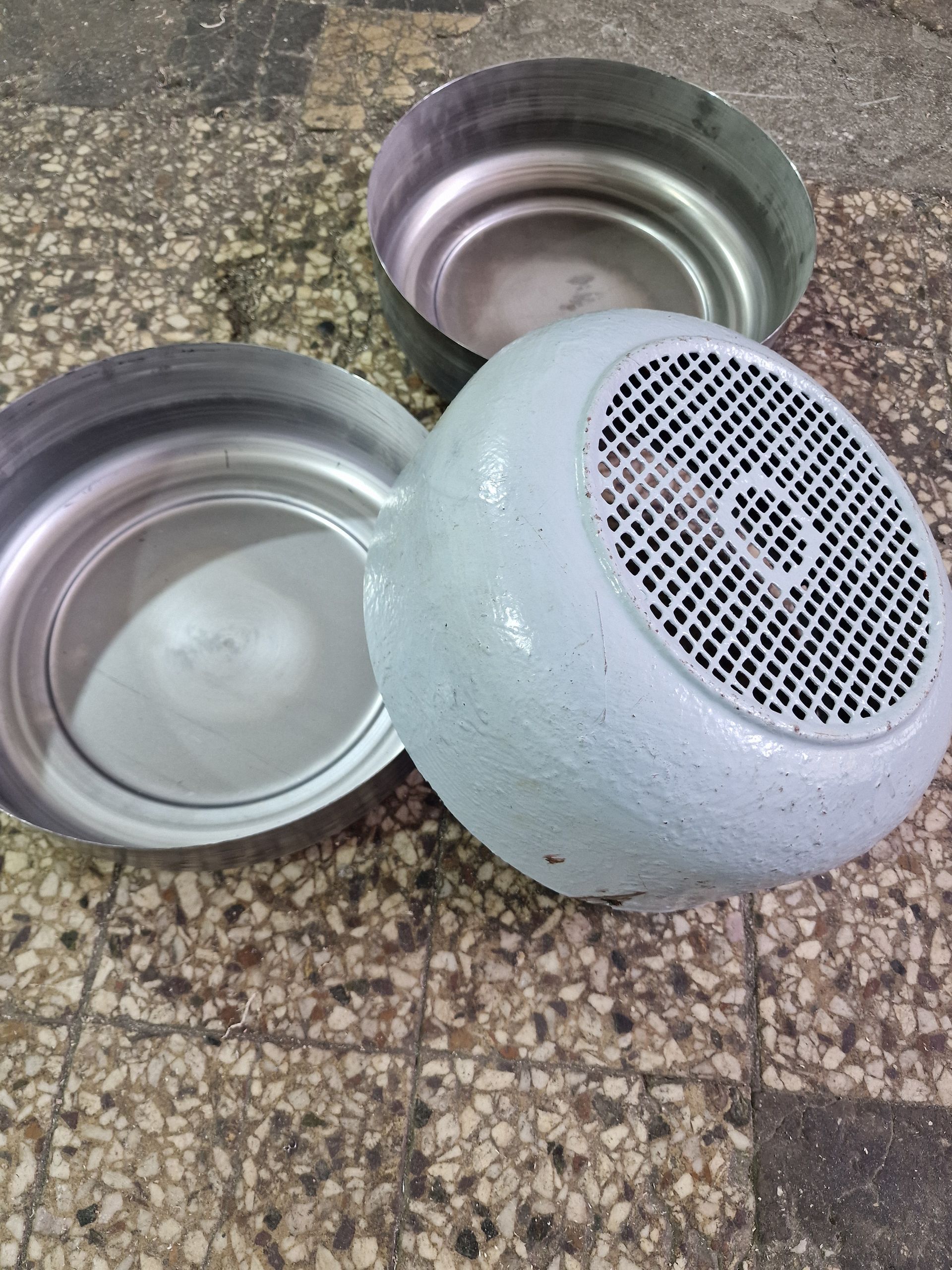 Τρία μεταλλικά μέρη κινητήρα σε ανάγλυφο δάπεδο. Το ένα μέρος έχει διάτρητο κάλυμμα και είναι βαμμένο.