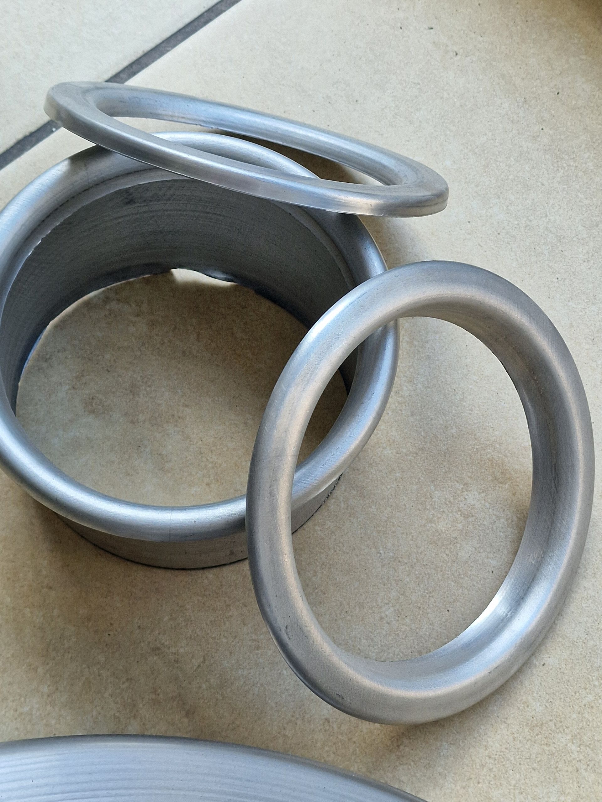 Αρκετοί κυκλικοί μεταλλικοί δακτύλιοι, μερικοί ένθετοι, σε μια ανοιχτόχρωμη επιφάνεια.