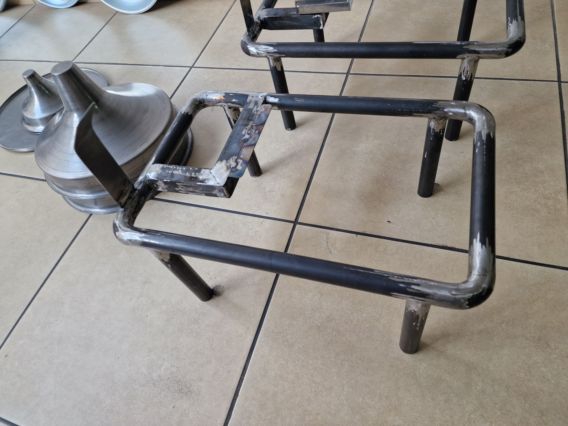 Μεταλλικές βάσεις και μεταλλικά δοχεία σε πλακόστρωτο δάπεδο. Μία βάση είναι στο επίκεντρο.