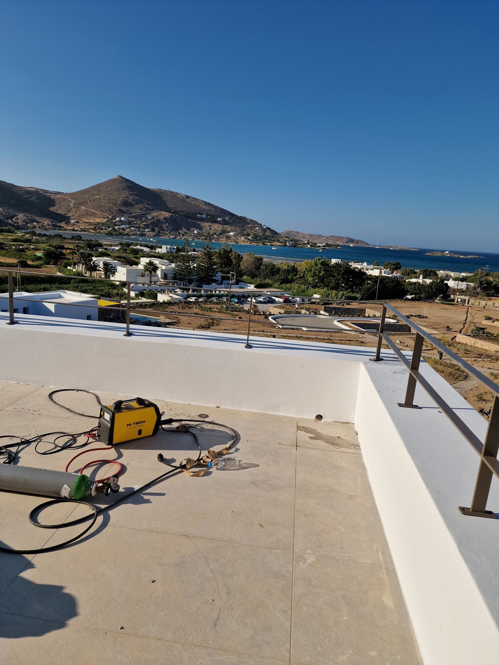 Ταράτσα με εξοπλισμό, με θέα σε μια παραθαλάσσια πόλη και τη γαλάζια θάλασσα κάτω από έναν καθαρό ουρανό.