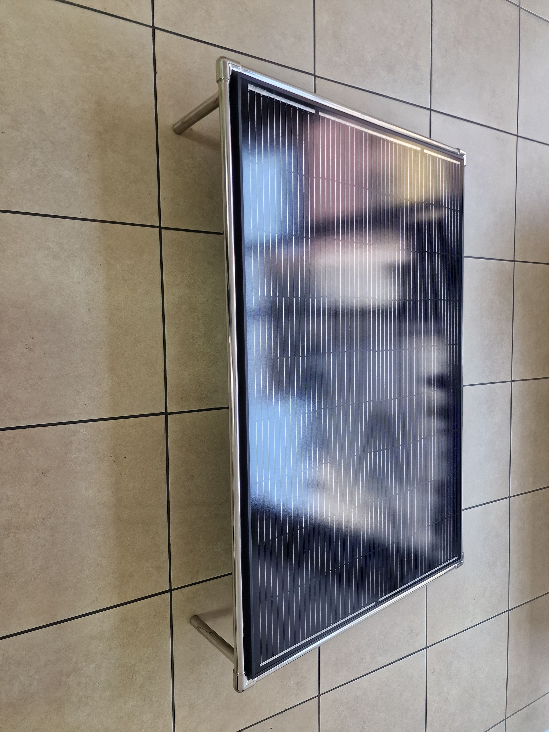 Ηλιακό πάνελ σε πλακόστρωτο δάπεδο, πλαισιωμένο με μέταλλο και κάθετες ρίγες.