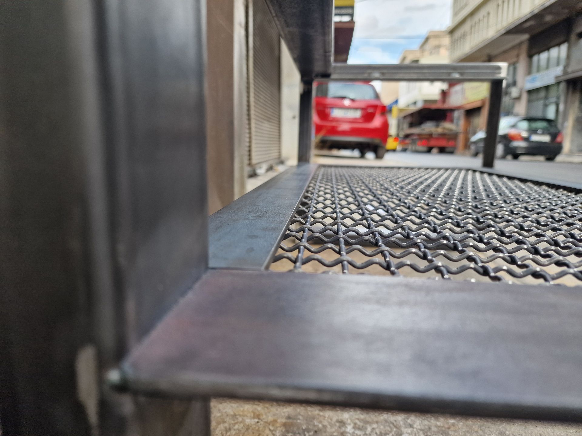 Μαύρη μεταλλική σχάρα με σκηνή δρόμου στο φόντο.