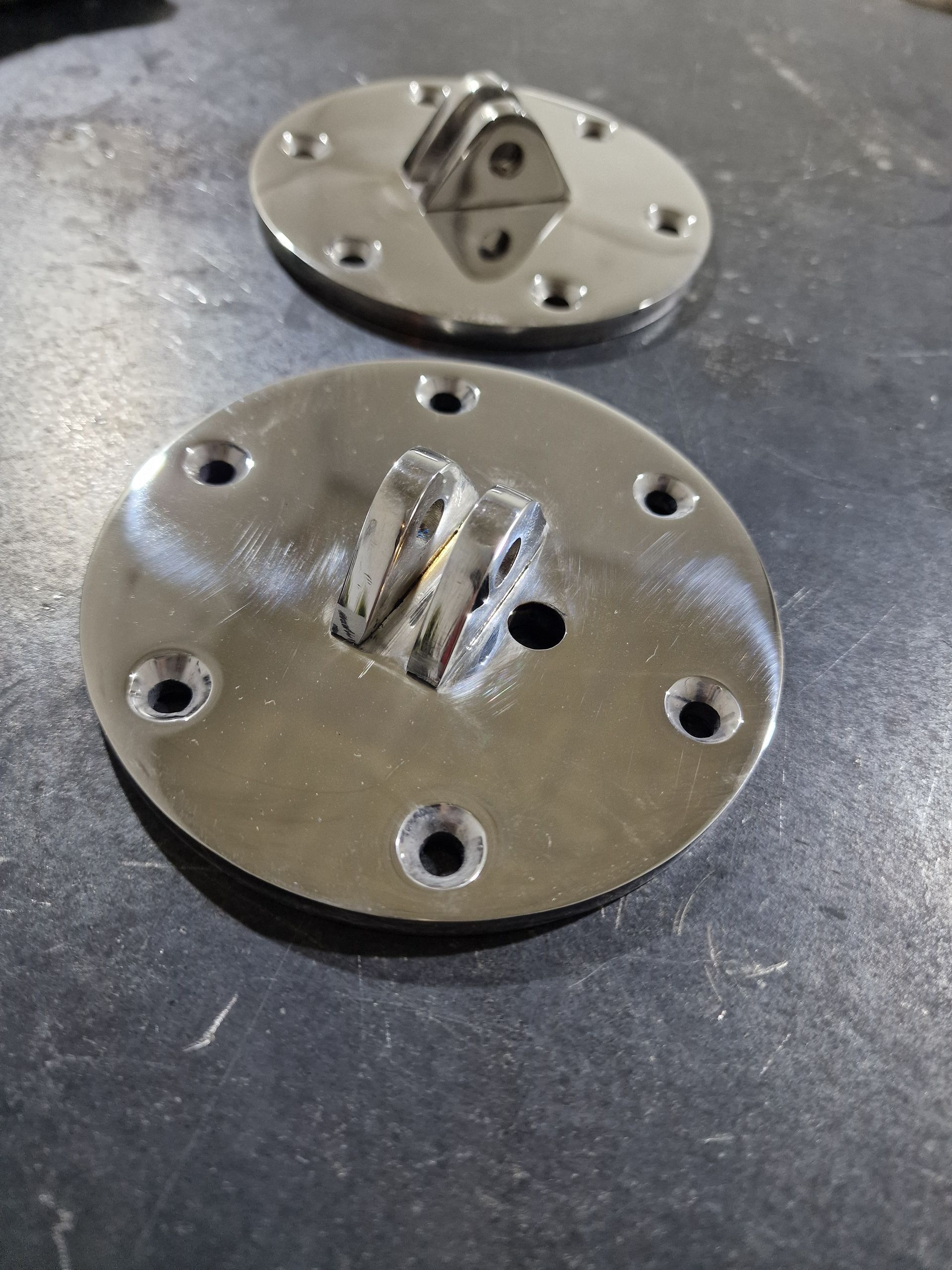 Δύο λαμπερές, κυκλικές μεταλλικές πλάκες με συγκολλημένο βραχίονα και αρκετές τρυπημένες τρύπες.