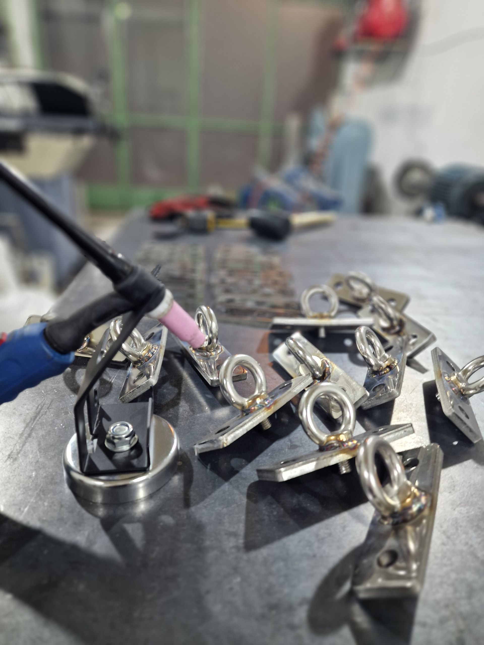 Συγκόλληση μεταλλικών τεμαχίων με ένα μπουλόνι με κρίκο προσαρτημένο σε ένα τραπέζι σε ένα εργαστήριο.