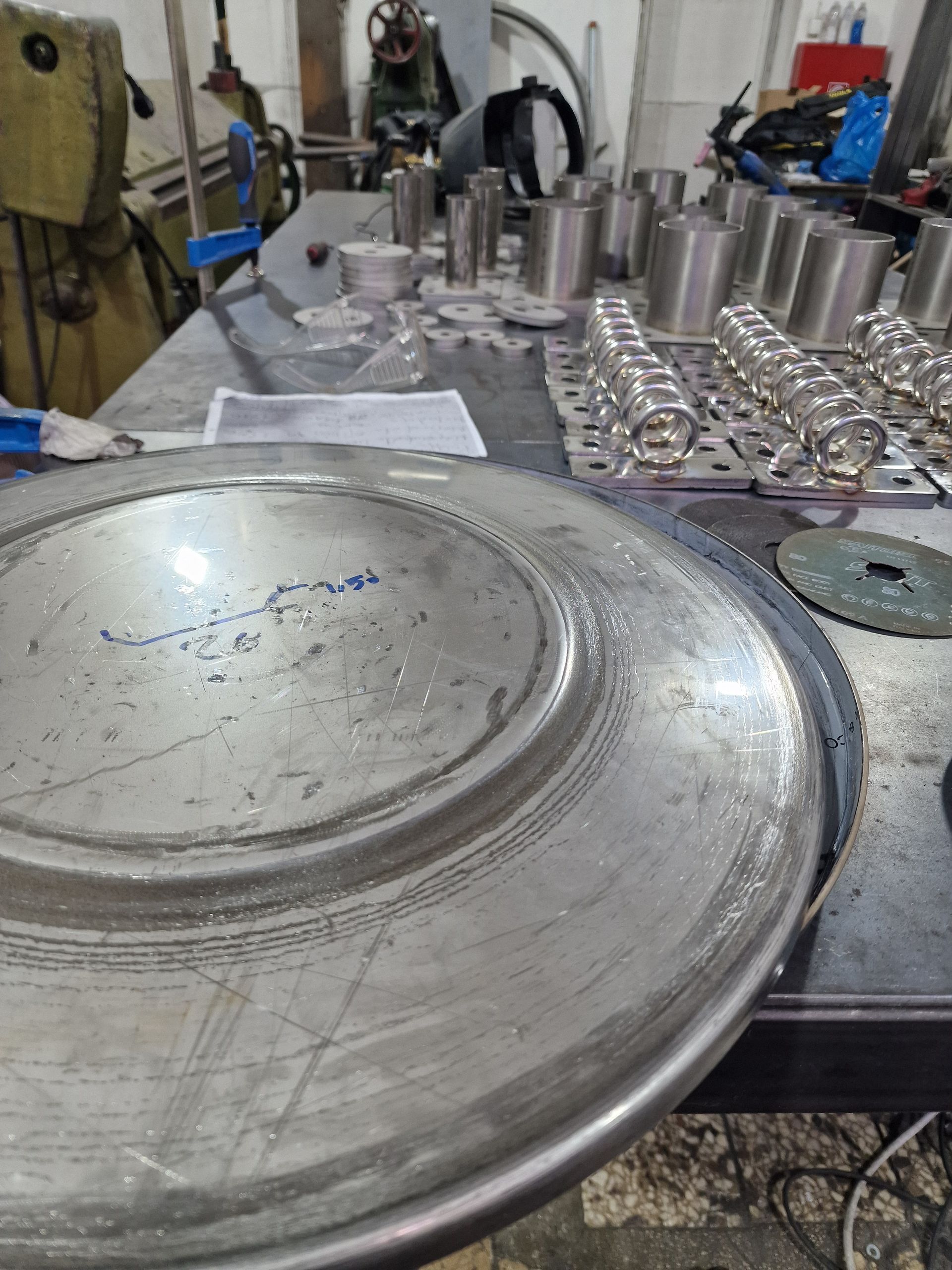 Μεταλλική πλάκα και κυλινδρικά αντικείμενα σε πάγκο εργασίας σε εργαστήριο.