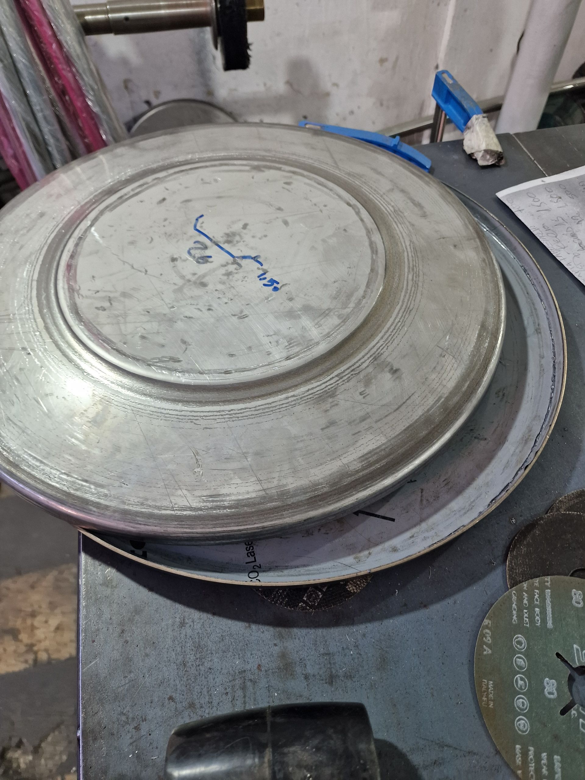 Δύο ασημένιες μεταλλικές πλάκες στοιβαγμένες σε μια σκούρα επιφάνεια εργασίας με εργαλεία κοντά.