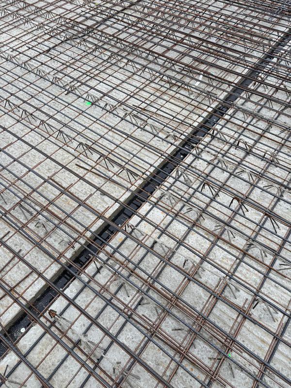 Im Bau befindliche Stahlbetondecke, erkennbar am Stahlbewehrungsgitter und einer dunklen Fuge.