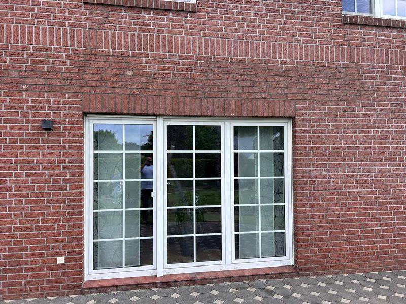 Fassade aus Backstein mit weiß gerahmten Fenstern.