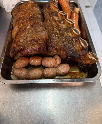 Menú de KAVARA BBQ con chuletón a la parrilla, guarniciones y logotipo sobre un fondo rústico oscuro.