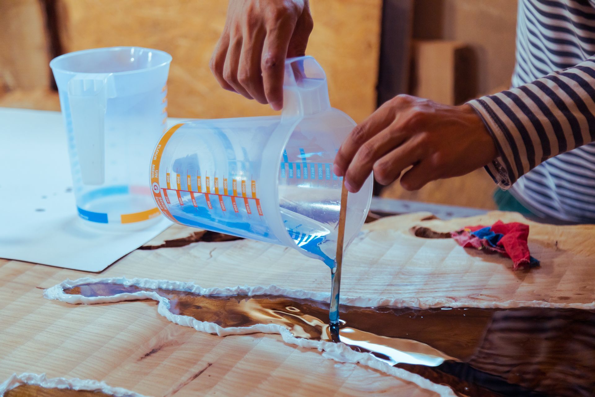 Eine Person gießt Harz in einen Holztisch.