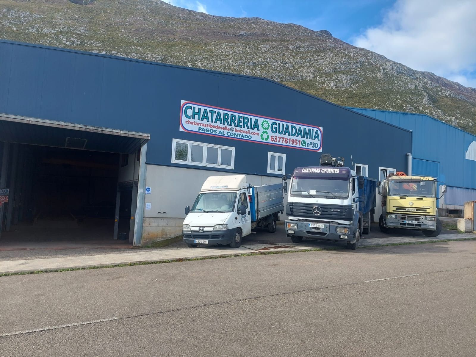 Tres camiones están estacionados frente a un edificio que dice chatarrería