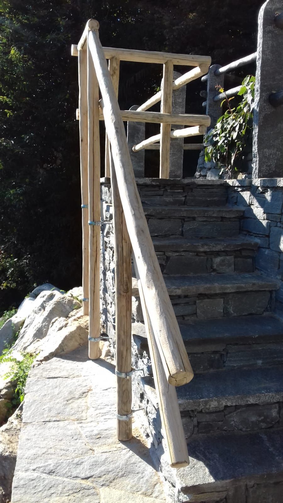 Gradini in pietra con corrimano in legno in un ambiente esterno.