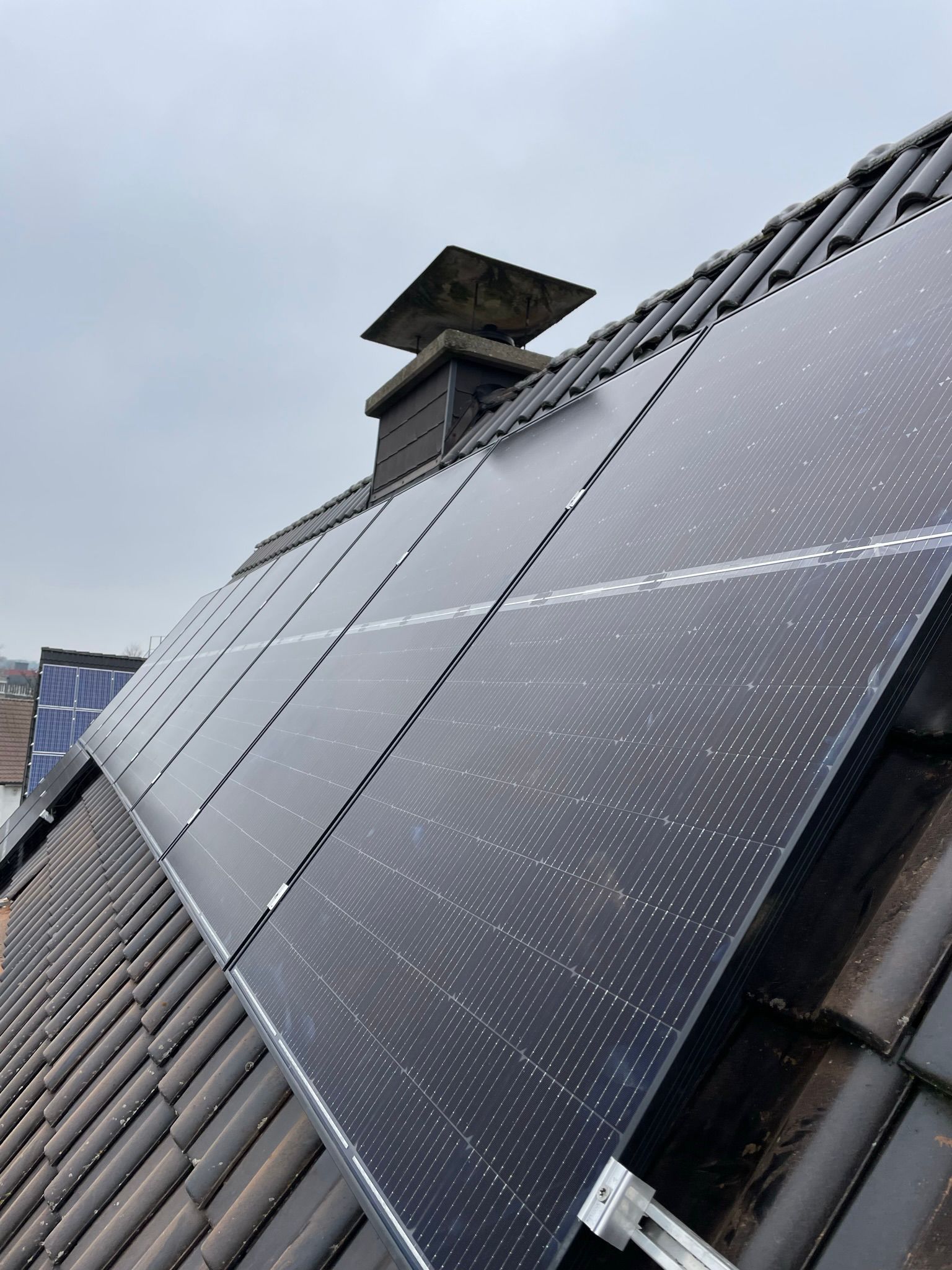 Auf einem Ziegeldach befindet sich eine Reihe von Solarmodulen.