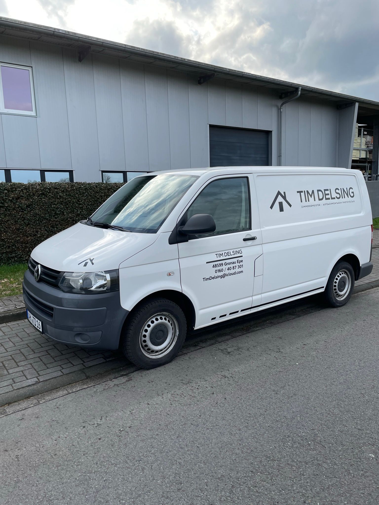 Ein weißer Lieferwagen steht am Straßenrand vor einem Gebäude.