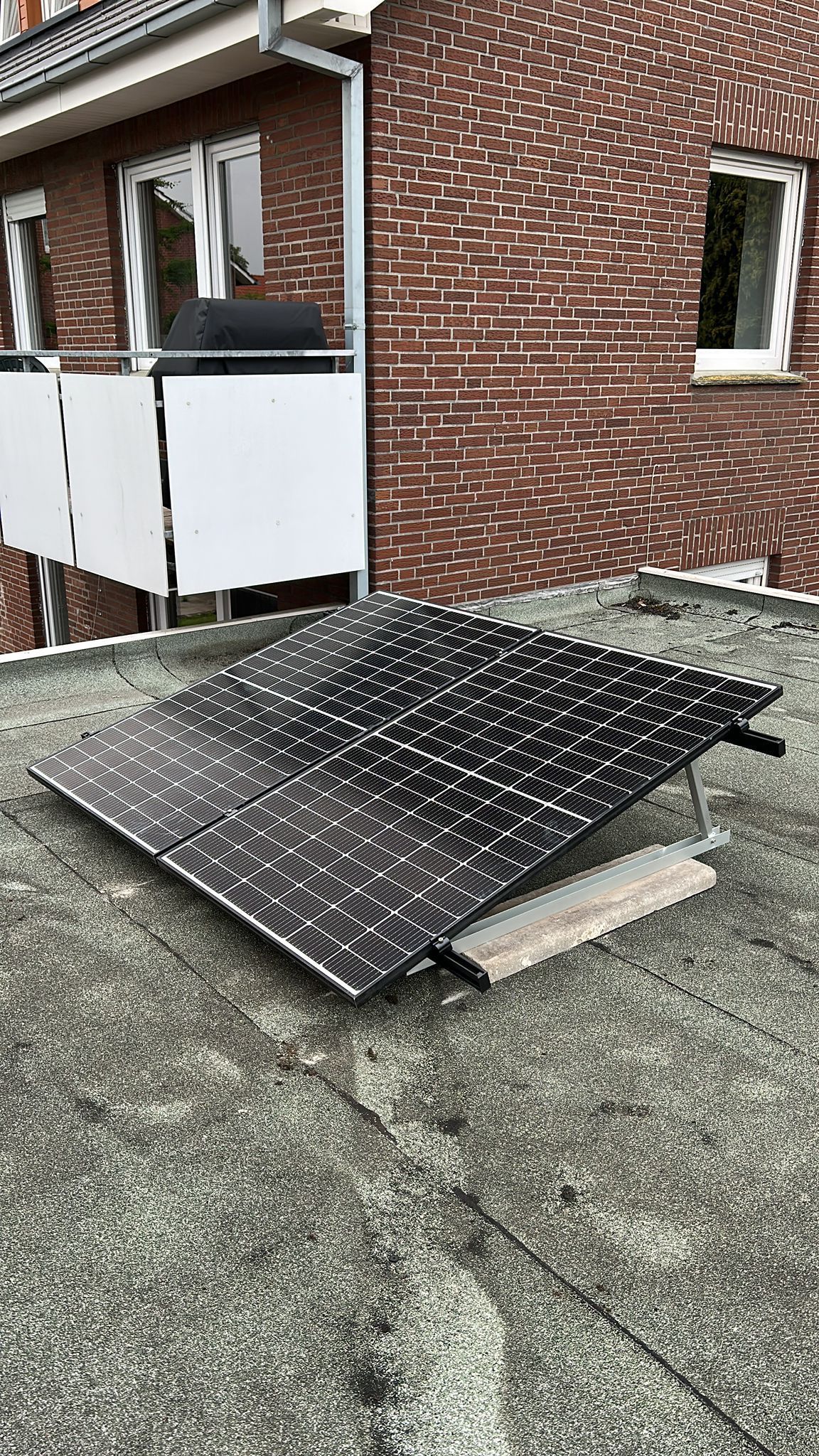 Auf dem Dach vor einem Backsteingebäude befindet sich ein Solarpanel.