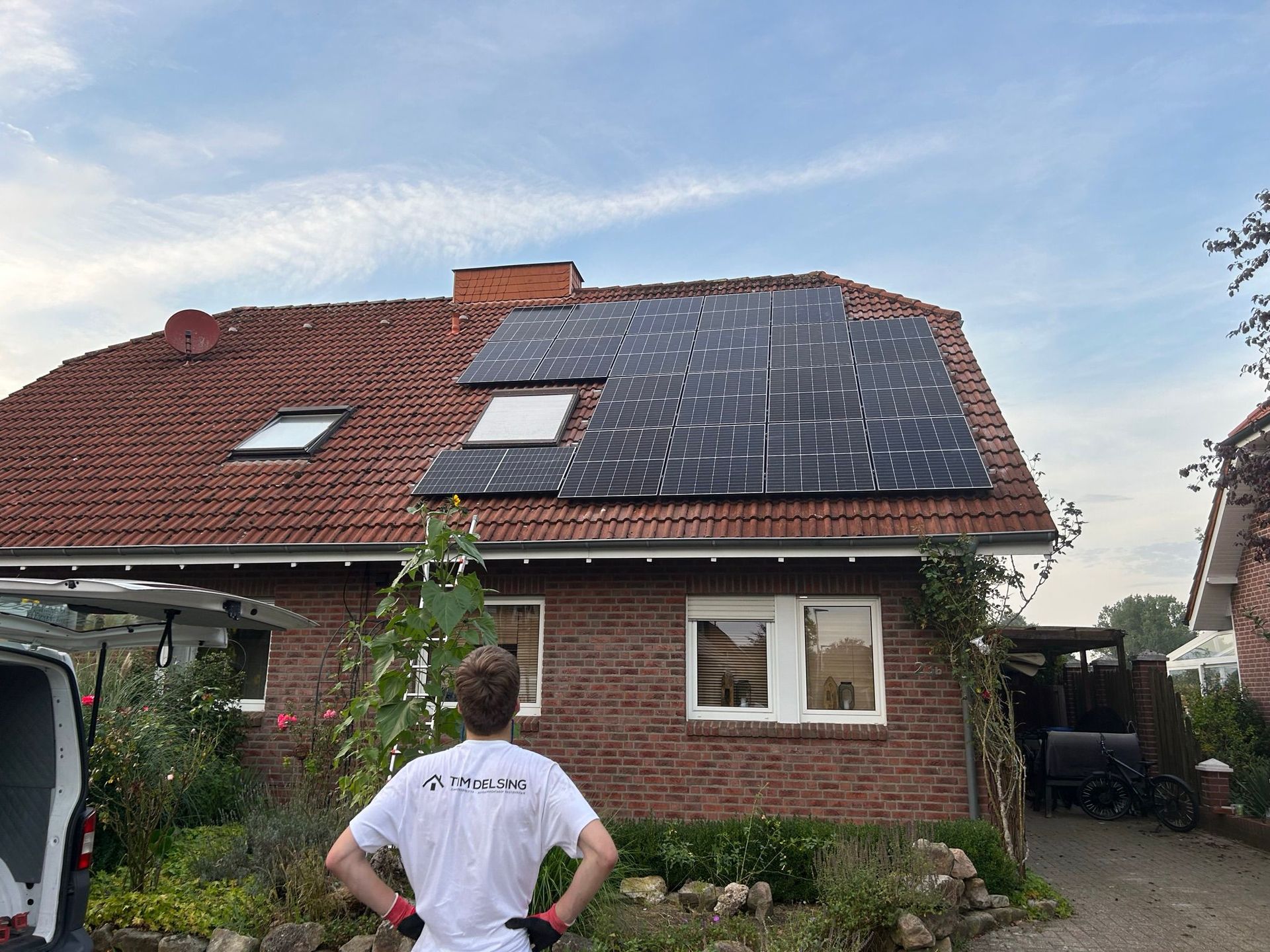 Ein Mann steht vor einem Haus mit Solarzellen auf dem Dach.
