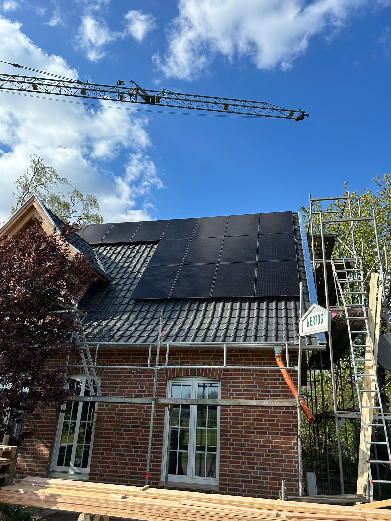 Es entsteht ein Backsteinhaus mit Sonnenkollektoren auf dem Dach.