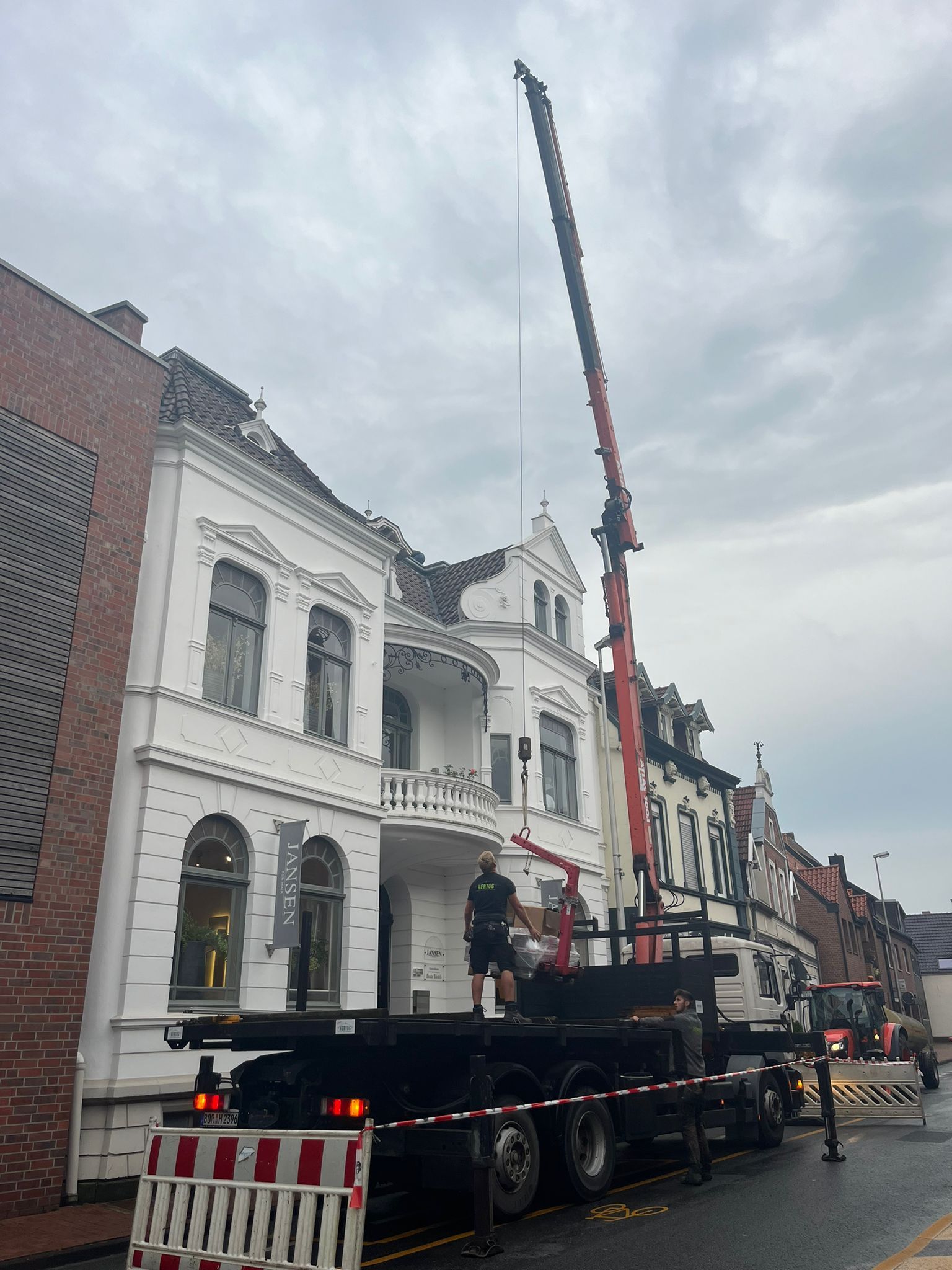 Vor einem Gebäude parkt ein LKW mit einem daran befestigten Kran.