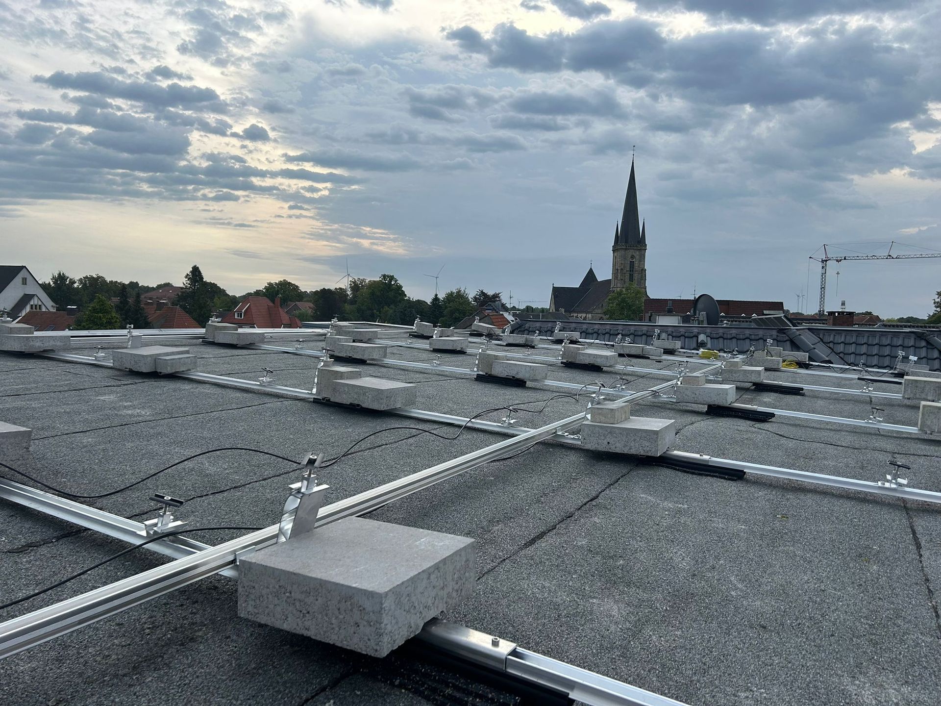 Ein Dach mit vielen Solarmodulen darauf und einer Kirche im Hintergrund.