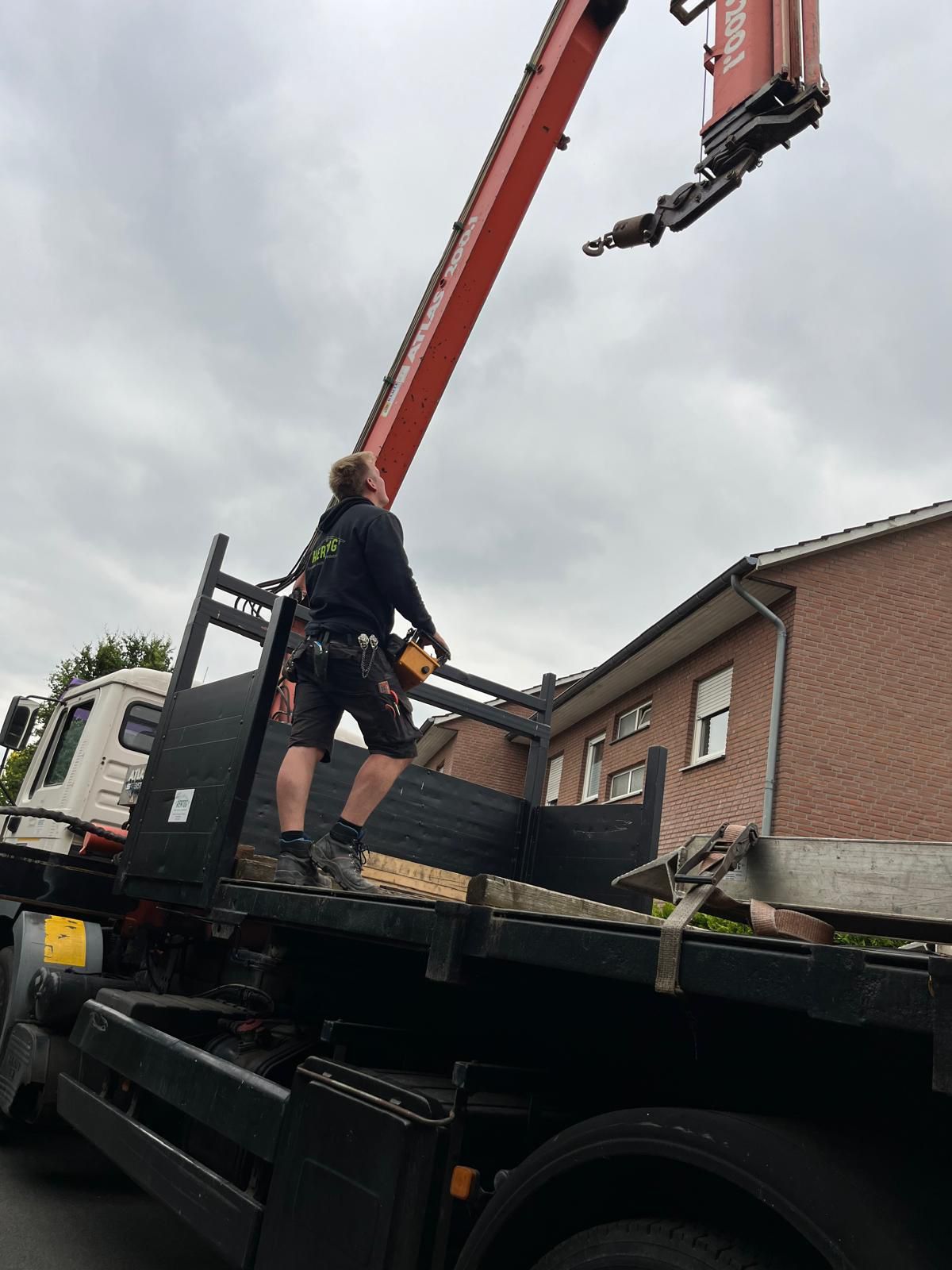 Ein Mann steht auf der Ladefläche eines Lastwagens, an dem ein Kran befestigt ist.