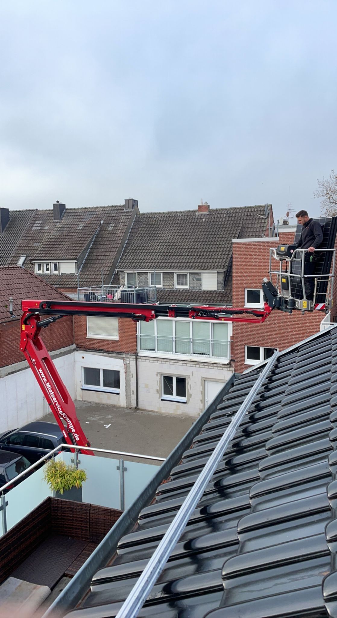 Ein Mann arbeitet mit einem Kran auf dem Dach eines Gebäudes.