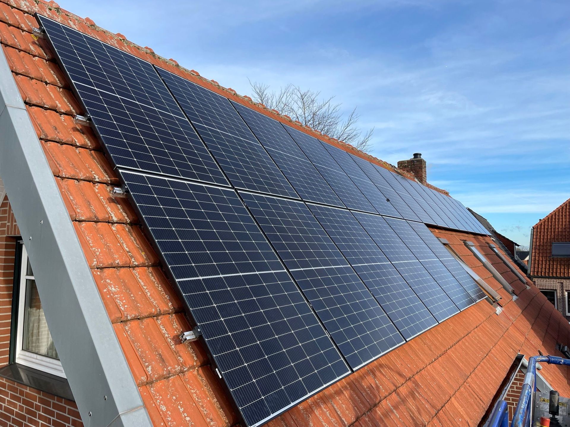 Auf einem Ziegeldach befindet sich eine Reihe von Solarmodulen.