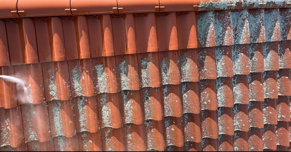 Eine Person reinigt ein Dach mit einem Hochdruckreiniger.