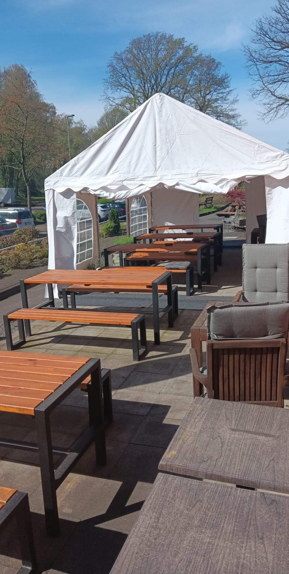 Eine Reihe von Holztischen und Bänken auf einer Terrasse