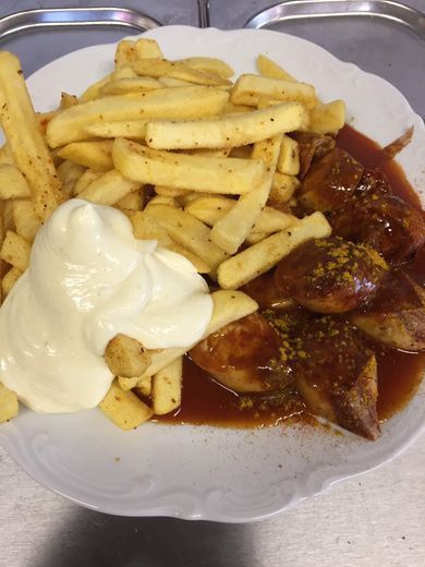 Ein Teller mit Essen: Pommes Frites mit Mayonnaise, dazu Currywurst.