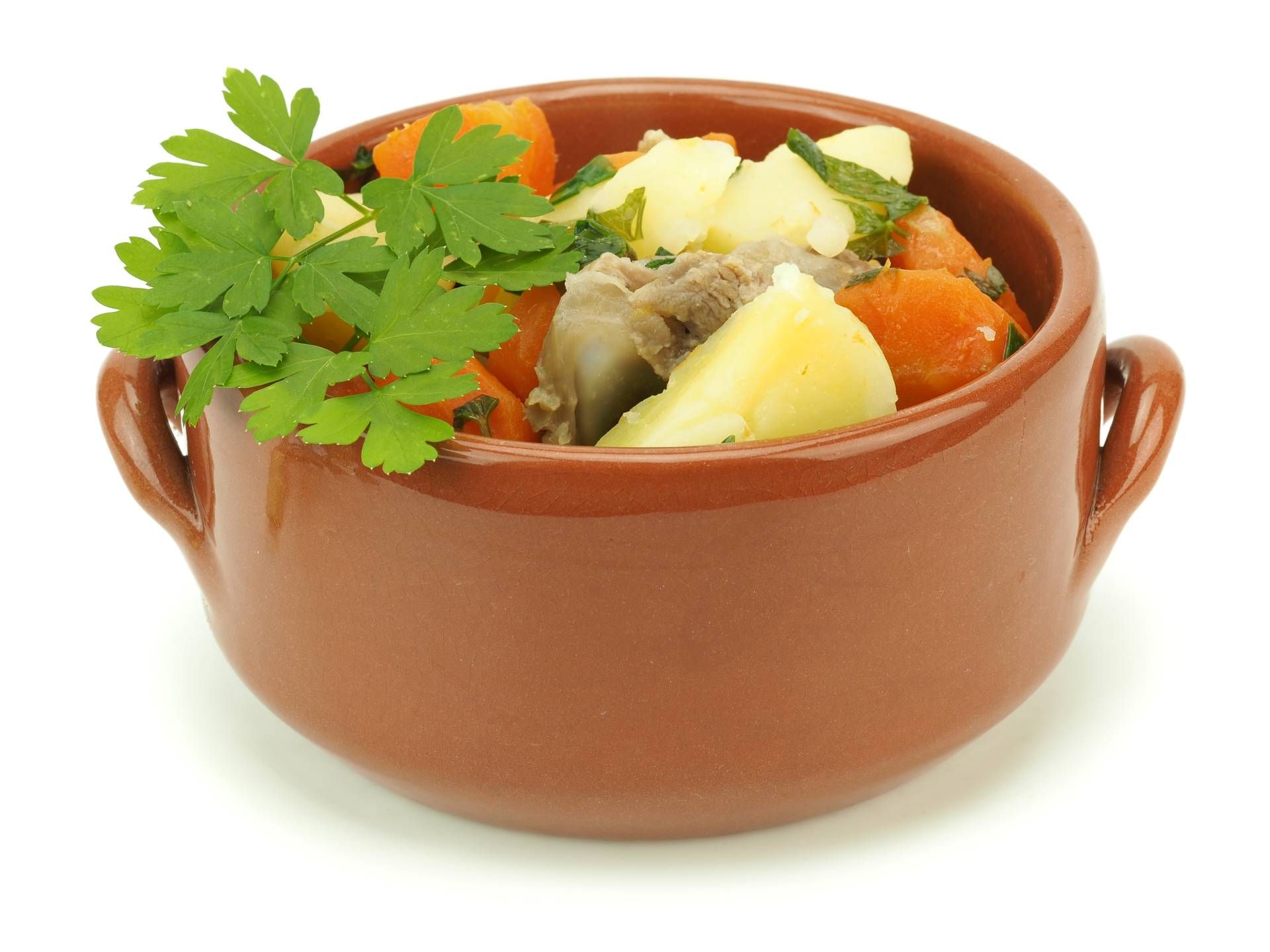 Eine Schüssel Eintopf mit Karotten, Kartoffeln und Petersilie obendrauf.