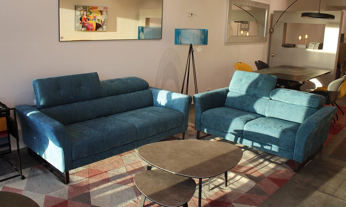 Salon aménagé avec deux canapés bleus, une table basse gigogne, un lampadaire et un tapis