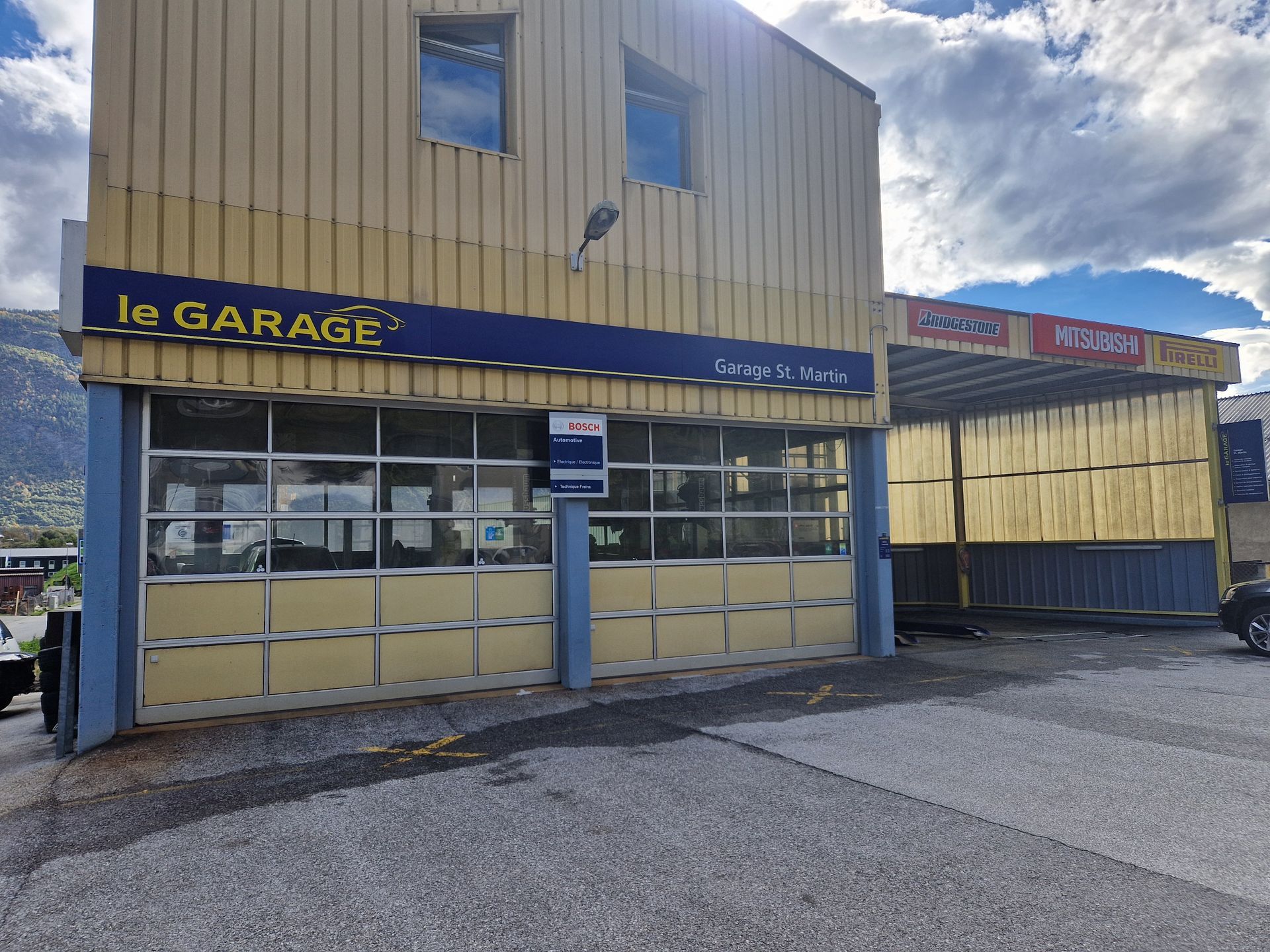 Un bâtiment jaune avec un panneau bleu indiquant le garage